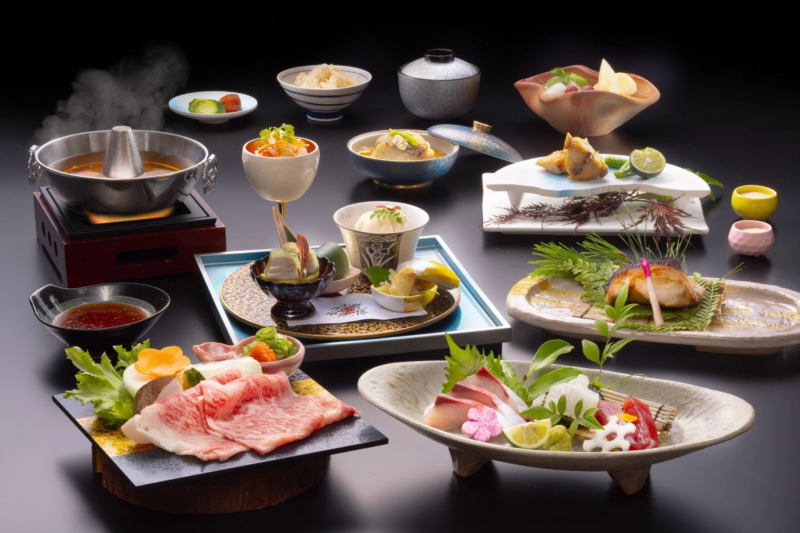 黒い背景に、美しく盛り付けられた豪華な懐石料理が並んでいます。鍋物、刺身、焼き魚、牛肉など、様々な種類の料理が陶器の器に盛られ、高級感あふれる日本の食卓を演出しています。