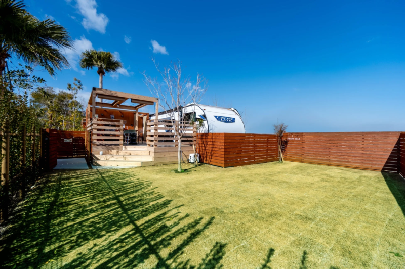 青空の下、キャンピングカーとウッドデッキ