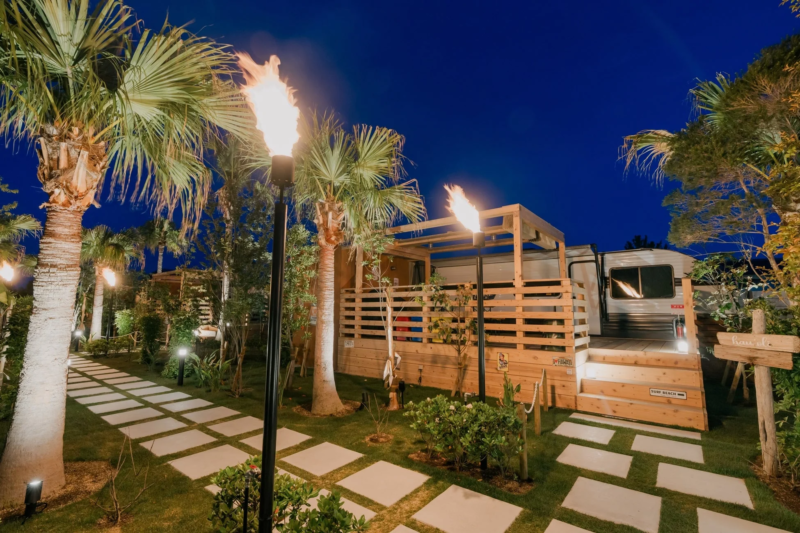 ヤシの木とトーチが並ぶ夜のグランピング施設