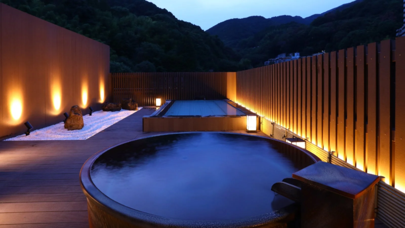 夕暮れ時、山々を背景にした露天風呂の風景