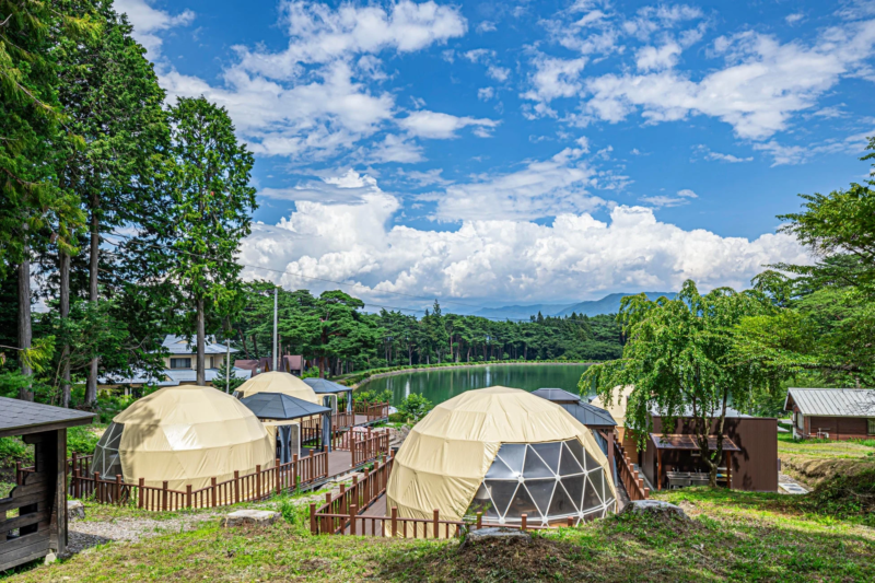 湖畔に広がるドームテントのグランピング施設