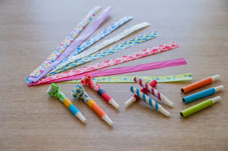 木製のテーブルの上に、カラフルなパーティーホーンとその紙製の部品