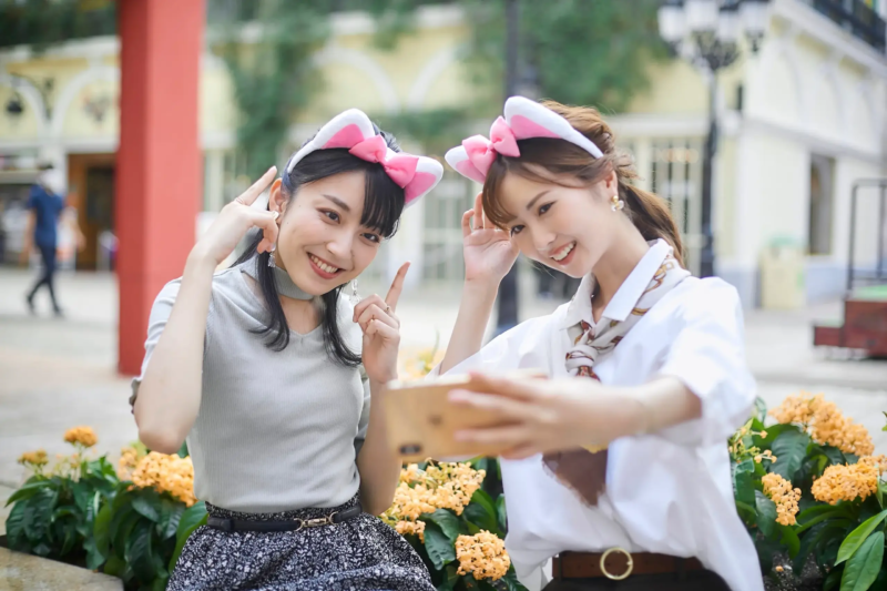 猫耳のカチューシャをつけた二人の若い女性がセルフィーを撮っている様子