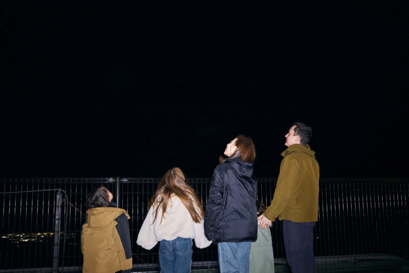 暗い夜空を見上げる4人の人物