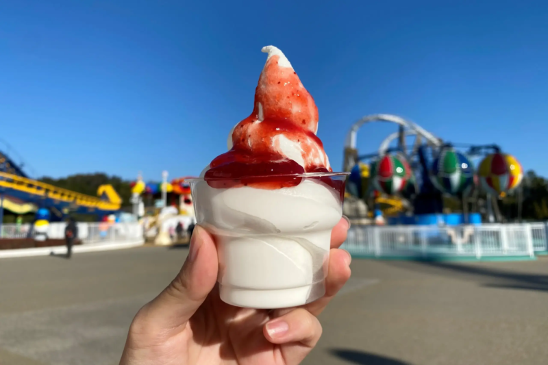 青空を背景にいちごソースがかかったソフトクリーム