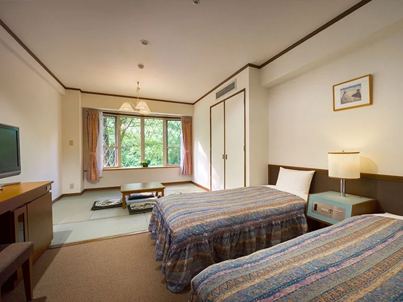 ツインベッドと畳スペースが融合した和洋室のホテル客室です。