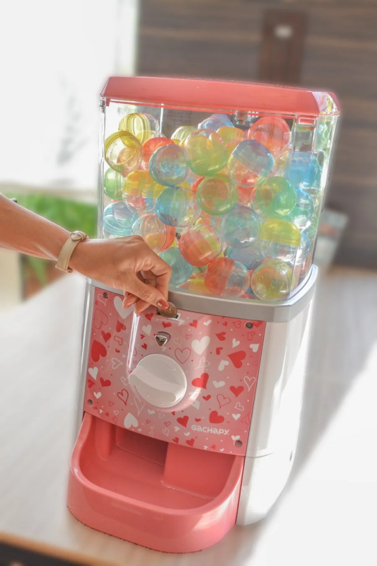 カラフルなカプセルが入ったピンク色のガチャガチャ