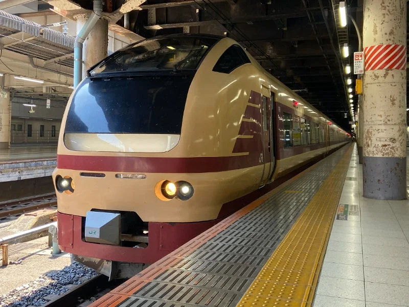 日本の駅のホームに停車しているクリーム色と赤色の特急列車