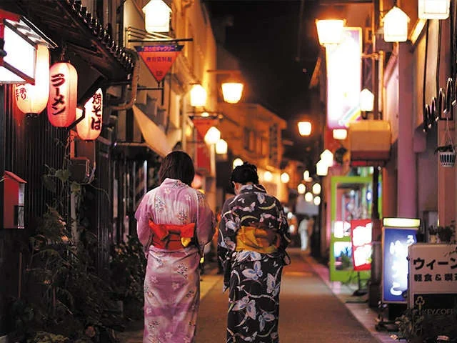 夜の日本の小道を浴衣を着た女性が歩く