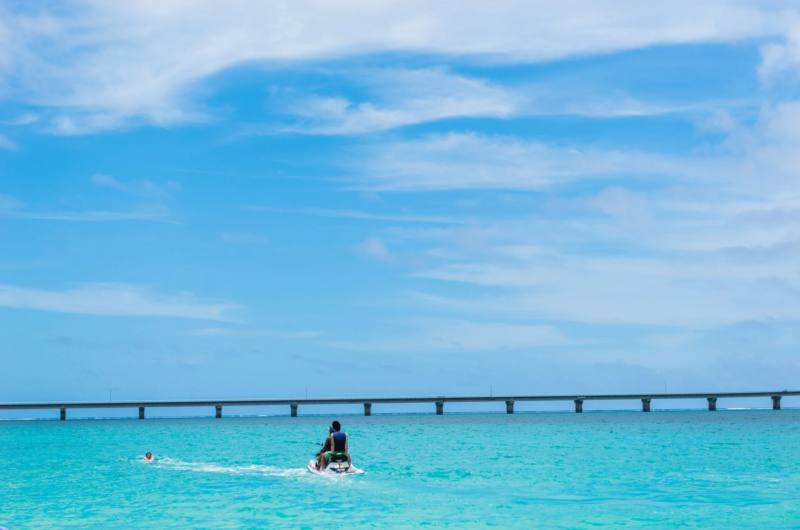 エメラルドグリーンの海でジェットスキーと遊泳を楽しむ人々