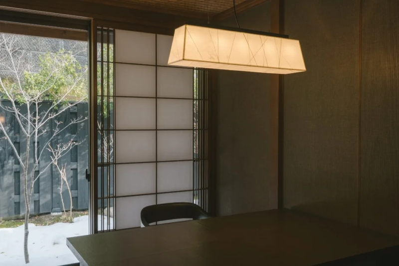 障子戸の向こうに雪が残る庭園が見える和室