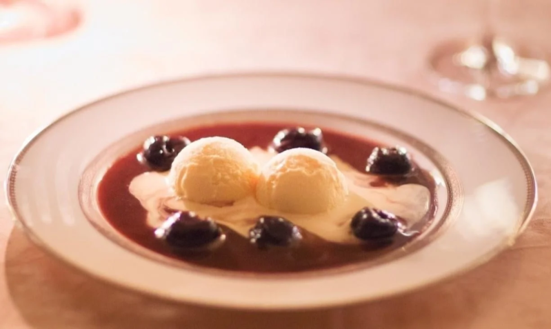 白い皿に盛られたバニラアイスクリームとチェリーのデザート