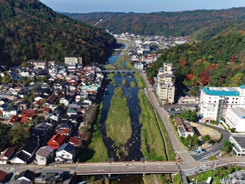 紅葉が始まった山々に囲まれた渓谷に広がる日本の街並み
