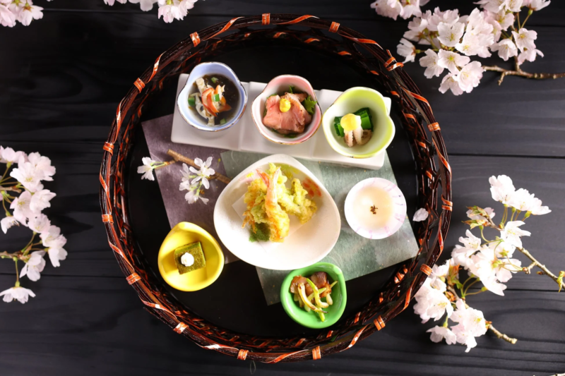 桜の花が添えられた美しい竹かごの中の和食膳