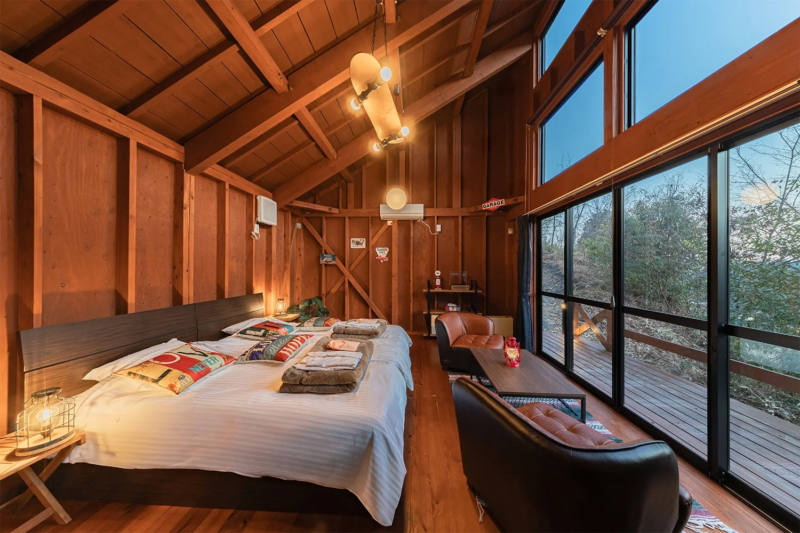 木製の壁と天井が特徴的な、居心地の良い寝室兼リビングスペースです