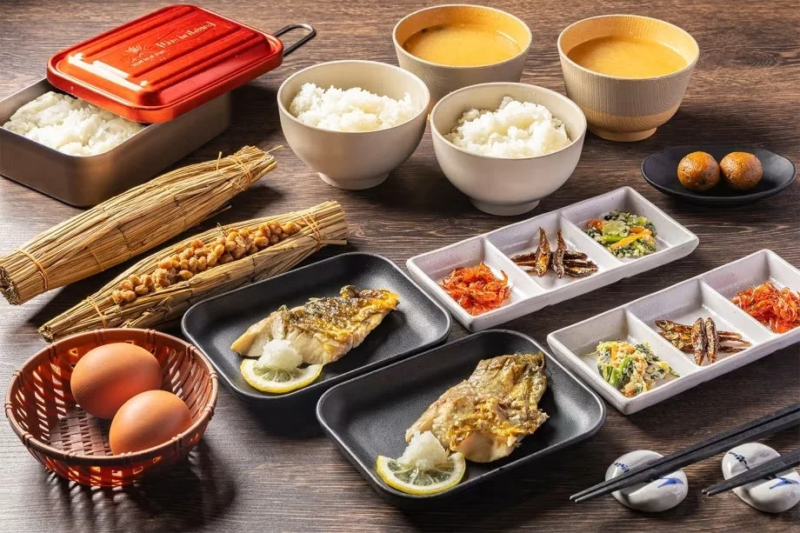 ご飯、味噌汁、焼き魚、納豆、卵、小鉢など、品数豊富な伝統的な和定食