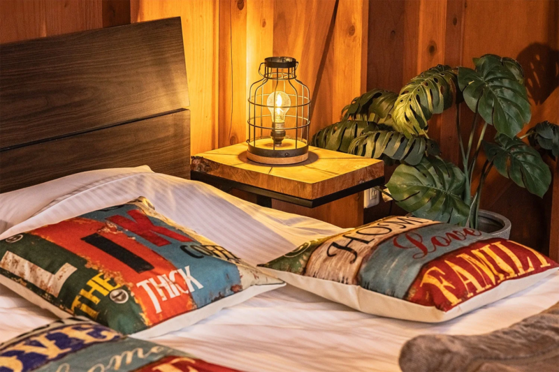 木製の壁と温かい光のランプがある寝室の様子