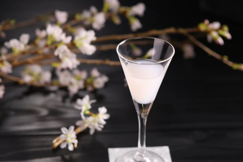 乳白色の液体が入ったマティーニグラスと桜の枝