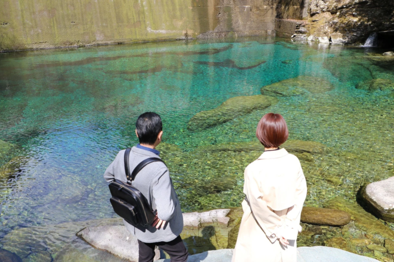 エメラルドグリーンの水辺を眺める二人