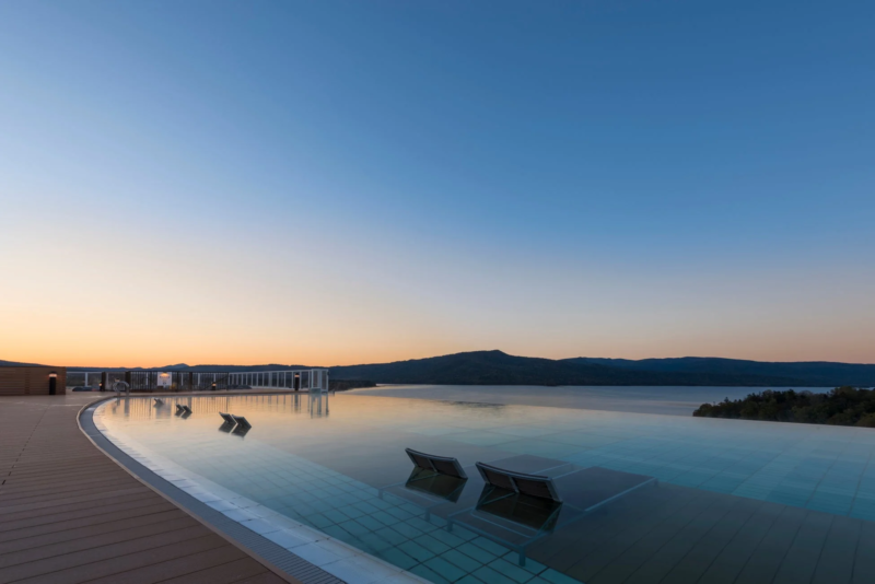 夕焼け空の下、湖と山々を望むインフィニティプール