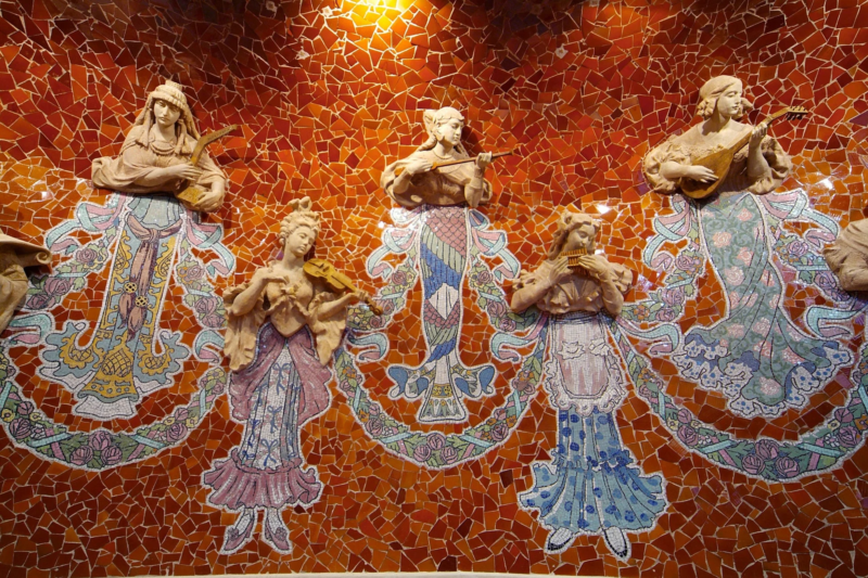 楽器を演奏する女性たちのレリーフが施された、オレンジ色のモザイクタイルで飾られた壁
