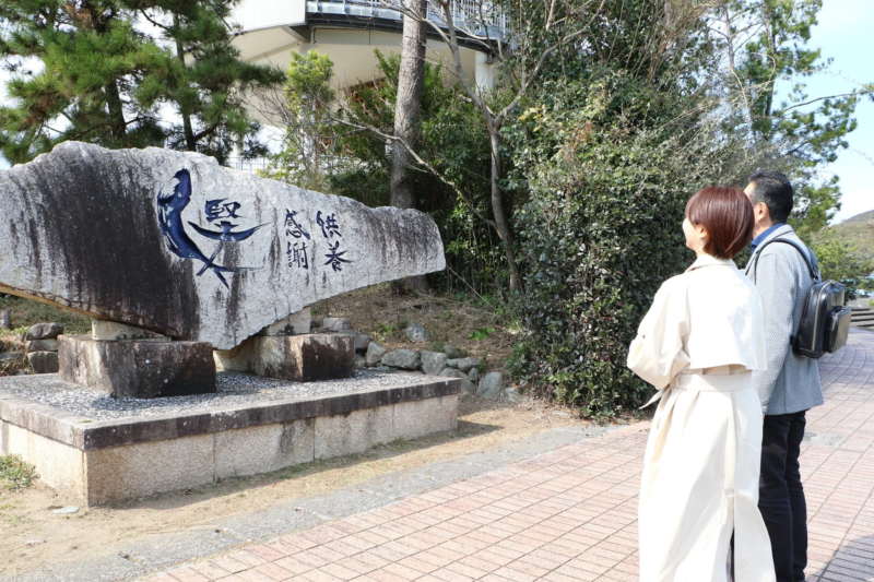 感謝と供養が刻まれた石碑を眺めるカップル