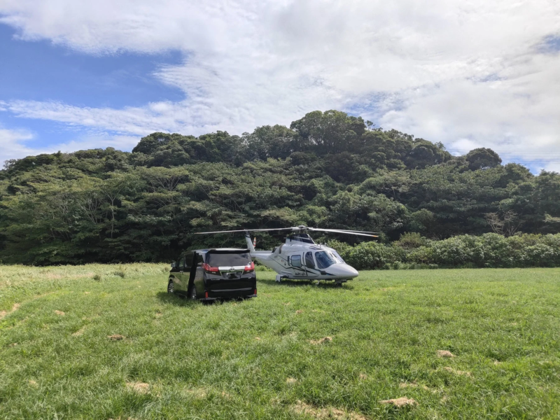 草原に並んで駐機するヘリコプターとバン