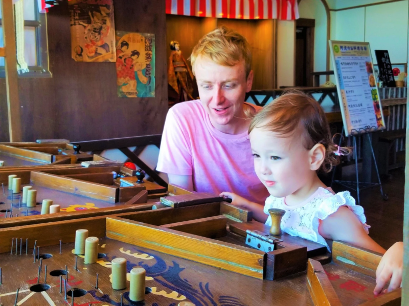 父親と幼い子供が、日本の伝統的な木製ゲームで遊んでいる様子