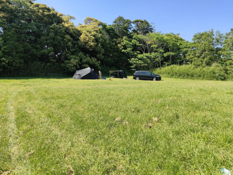 広々とした草原に設置されたテントとミニバン
