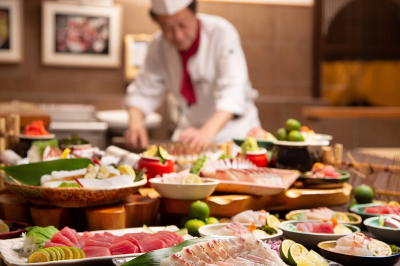 寿司職人が複数の新鮮な刺身や和食を準備している様子