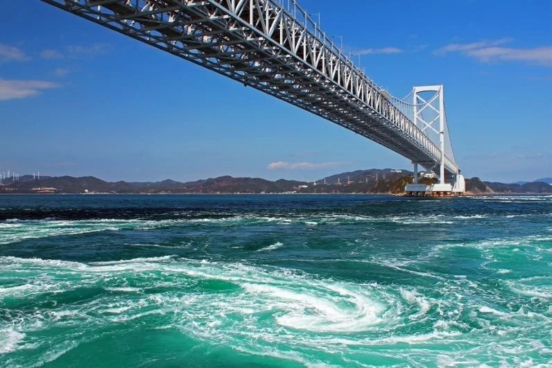 鳴門海峡にかかる鳴門大橋の下で、ダイナミックな渦潮が巻いている様子