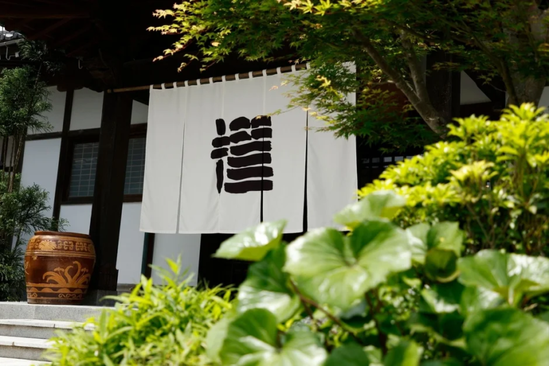 「龍」の文字が描かれた白い暖簾がかかる、伝統的な日本家屋の入り口