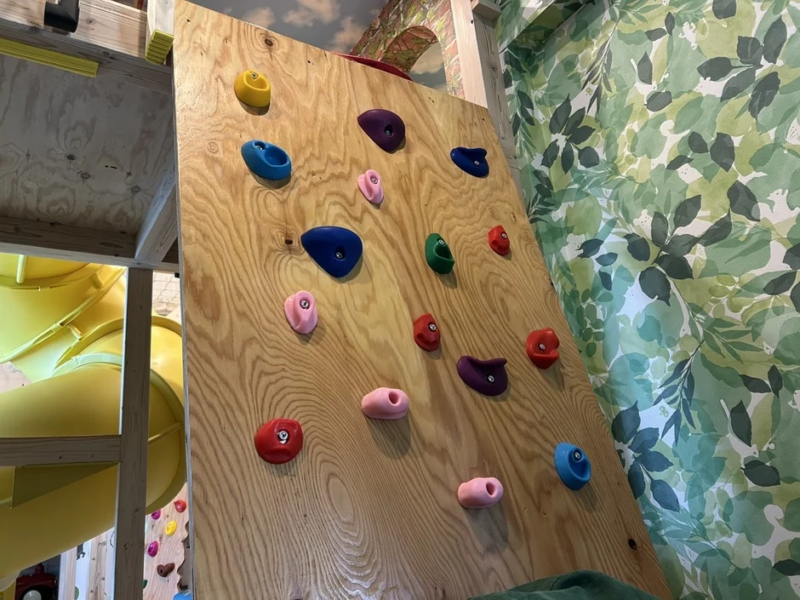 カラフルなクライミングウォールと黄色い滑り台がある子供部屋