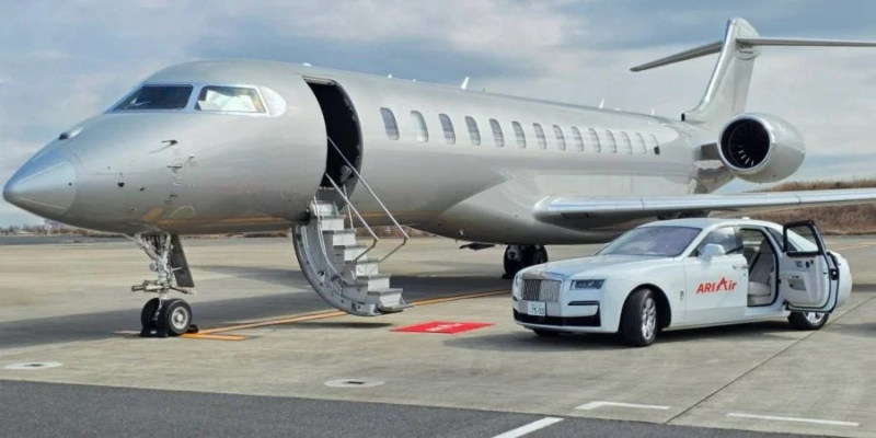 空港の駐機場に停められたシルバーのプライベートジェットと高級車